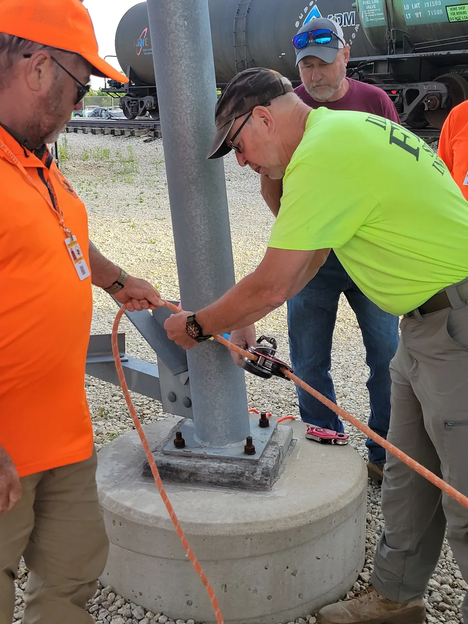 Team members practice tying rescue rope around a metal post.